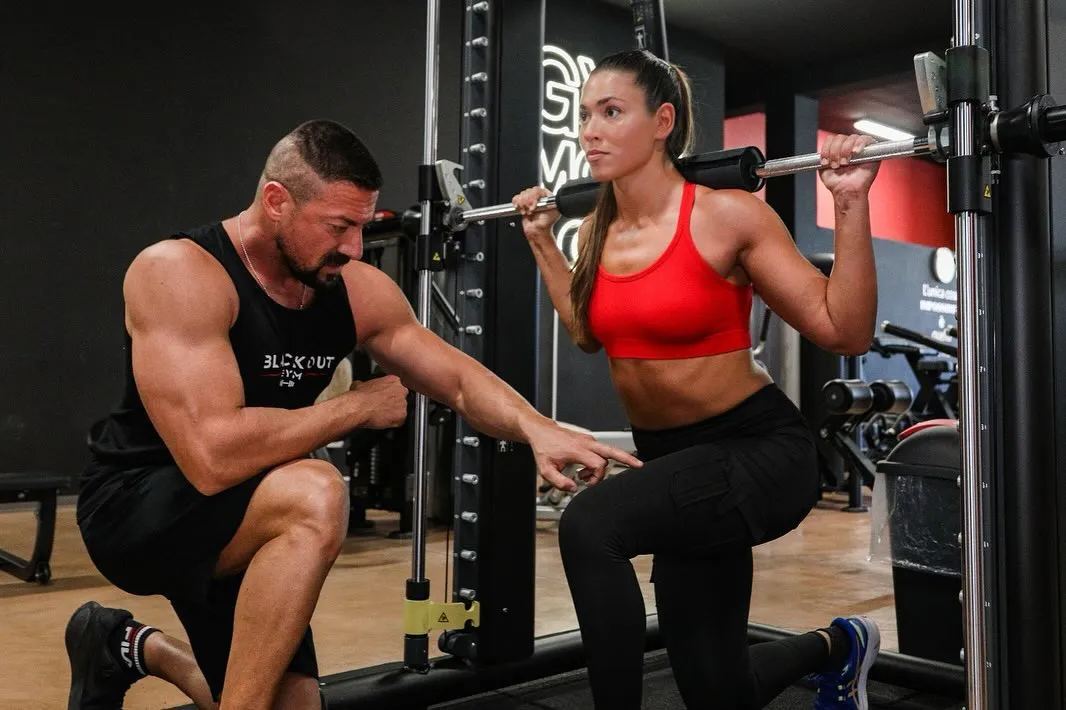 Personal trainer Blackout Gym che mostra l’esecuzione di un esercizio a una cliente
